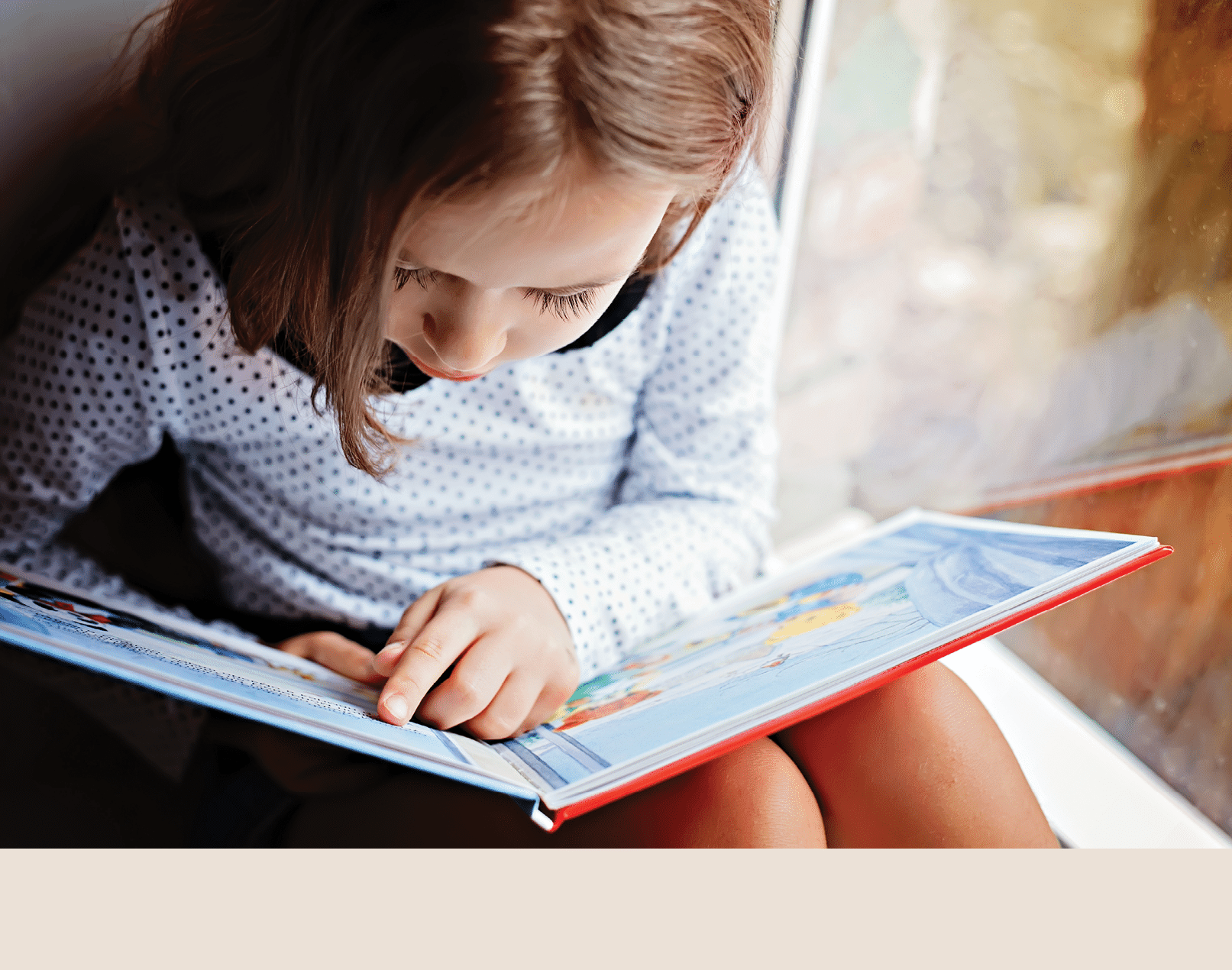 toddler girl with book near the window